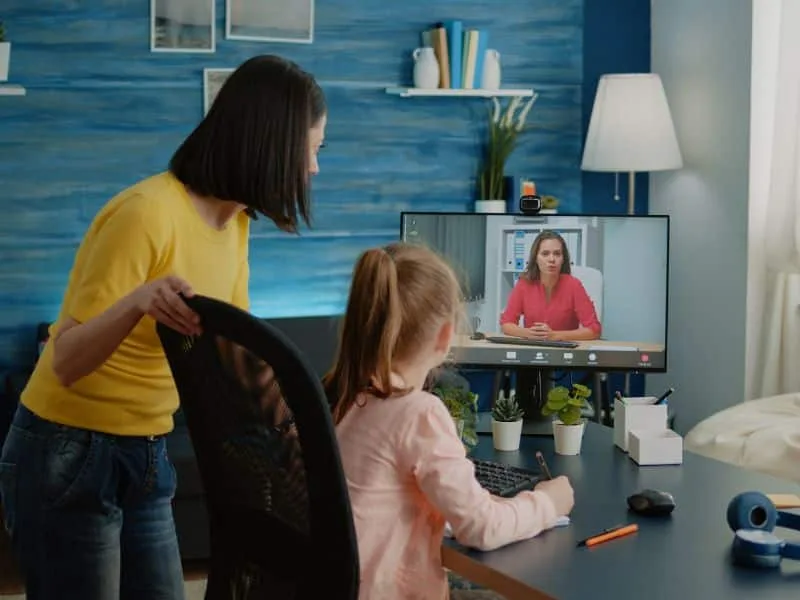 A nanny video chatting with a pediatrician while holding a young child.