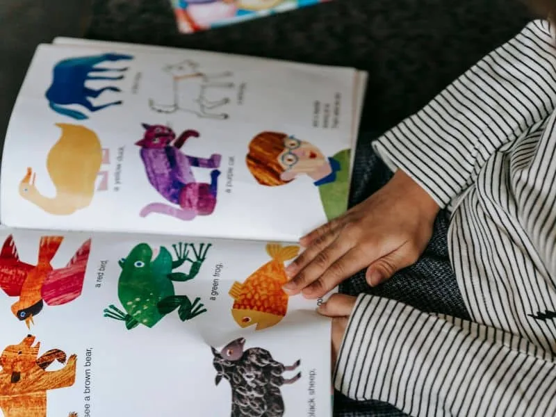 A nanny reading a bedtime story from a tablet while a child listens attentively.