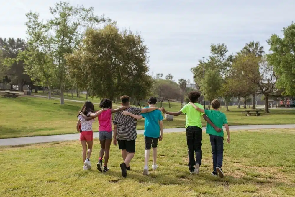 Kids on a nature walk during summer camp at the Houston Arboretum, observing insects and plants.