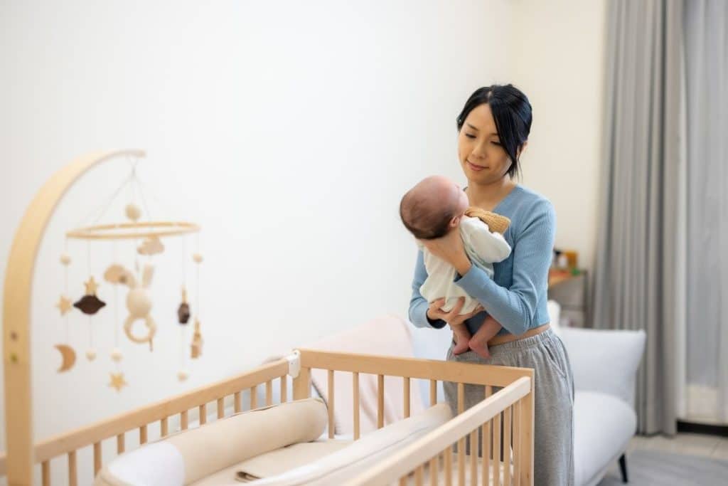 Overnight nanny gently placing a newborn into a crib while parents rest
