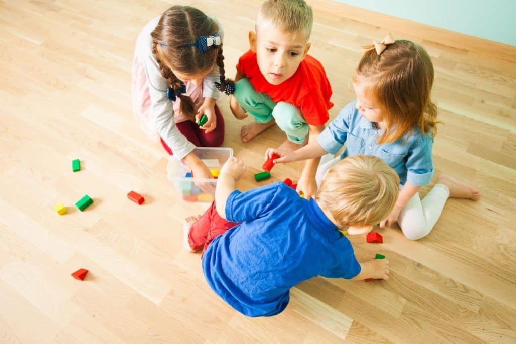 Young children helping each other clean up toys