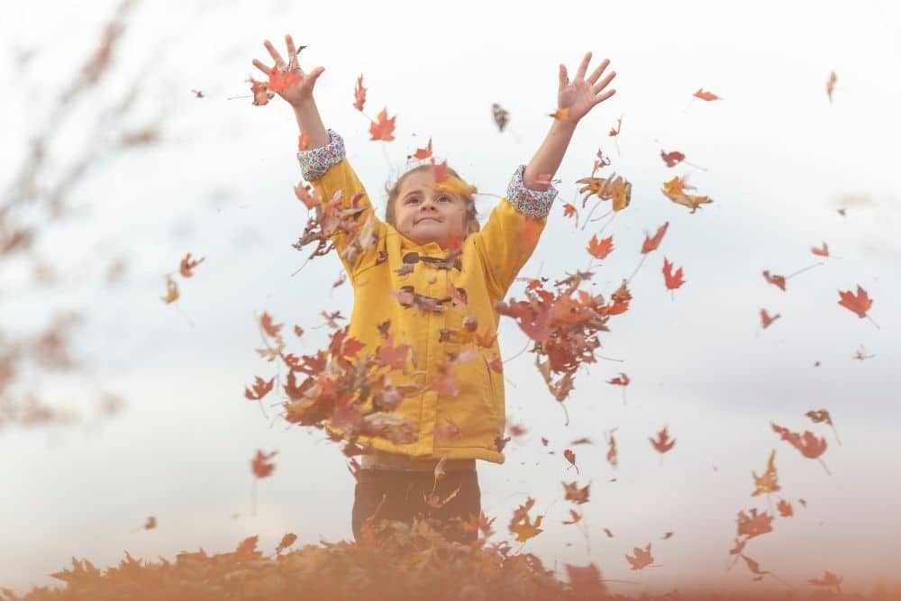 Nanny supervising kids in jackets playing safely at a Texas park during fall.