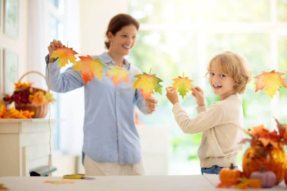 Texas family and nanny smiling together in an autumn-decorated living room.