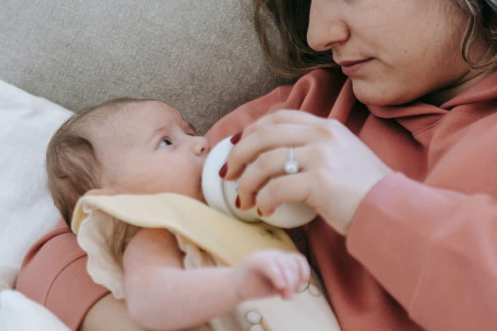 Newborn care specialist assisting parents with their baby in a peaceful nursery.