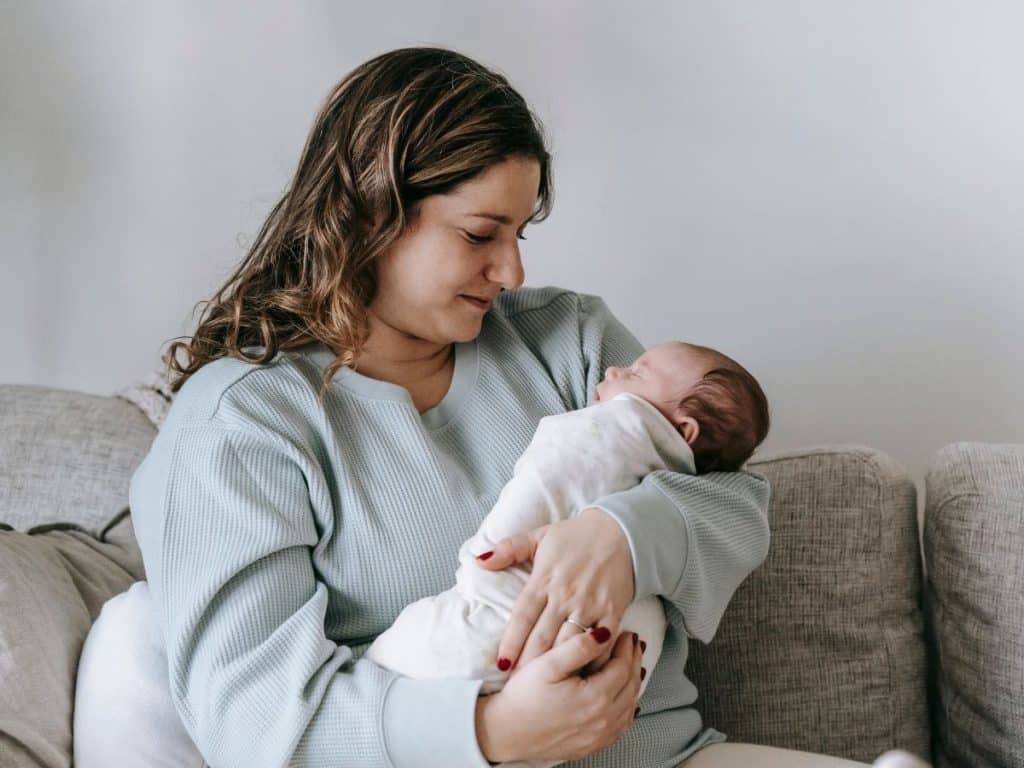 Newborn care specialist comforting a tired mother while holding her baby.