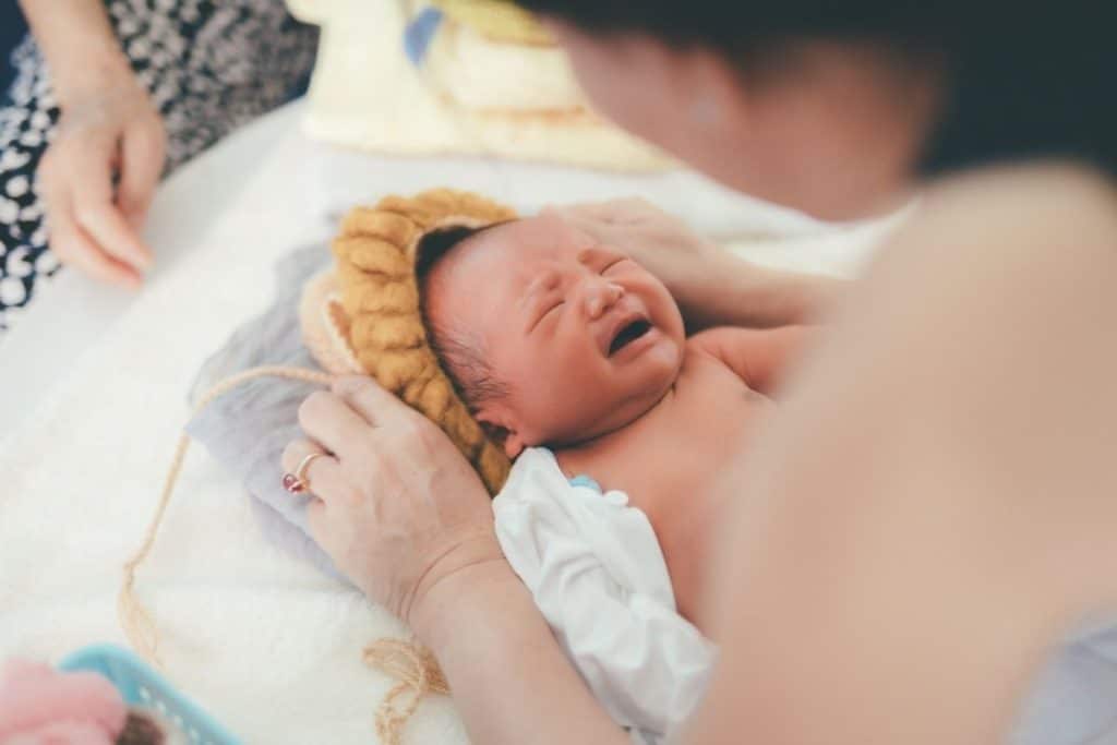 Night nanny or newborn care specialist tending to a baby in a softly lit nursery during an overnight shift.