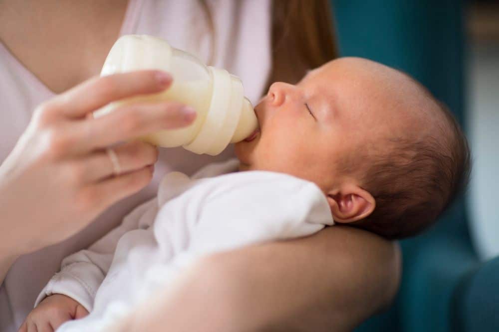 Night nanny feeding a baby with a bottle during nighttime hours