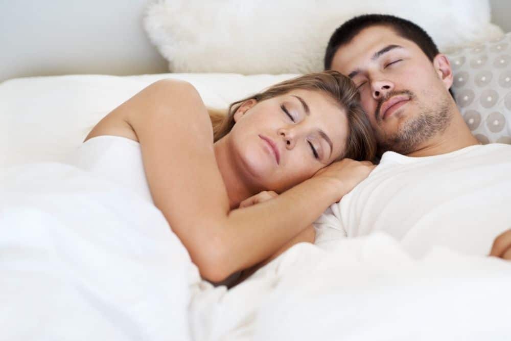 Parents resting peacefully while a night nanny cares for their newborn nearby