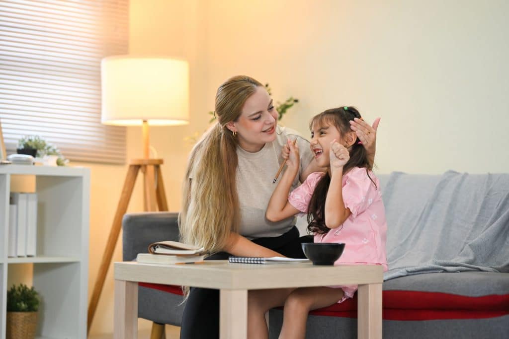 Experienced nanny helping a child with an educational activity in a bright playroom.