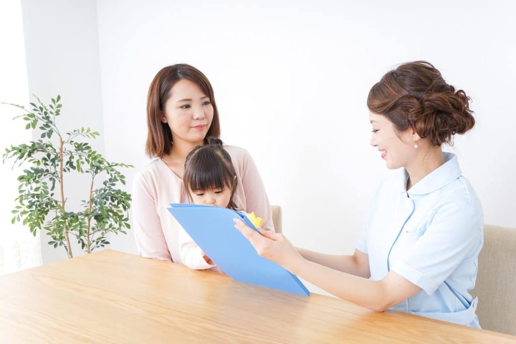 Parents and nanny reviewing and signing a childcare service agreement.