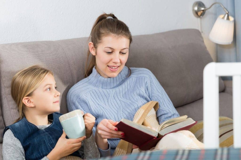 Young child comfortably reading with long-term nanny in calm home environment