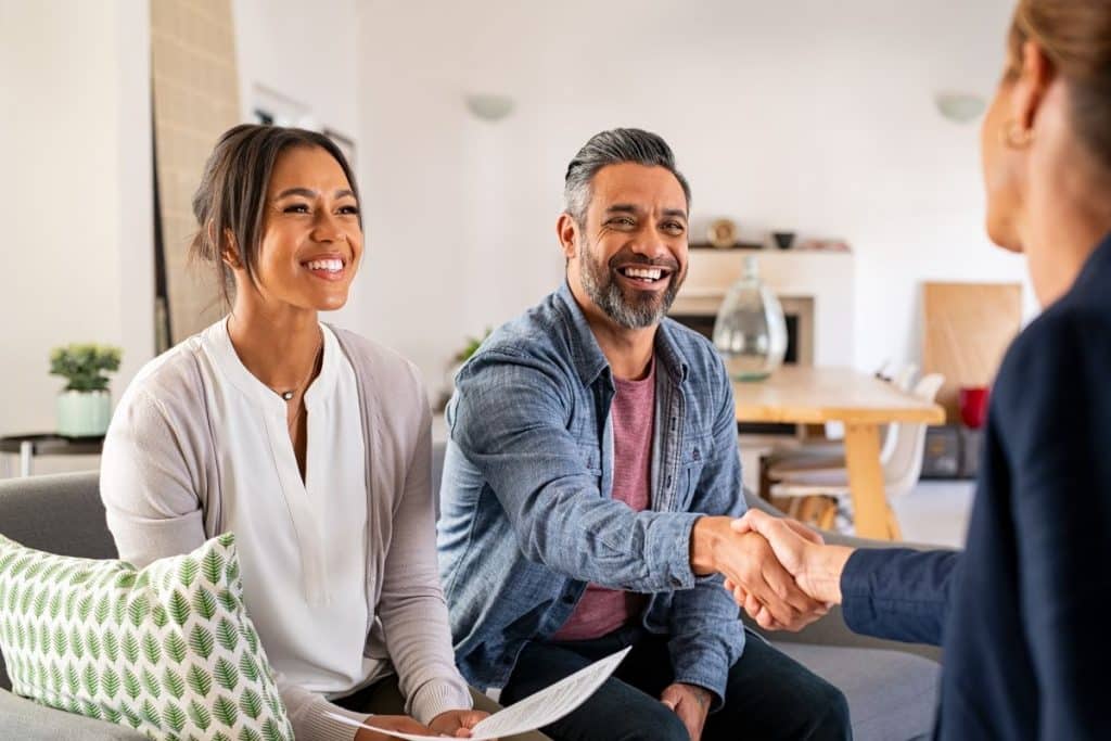 Family interviewing nanny candidate in home environment while child interacts nearby