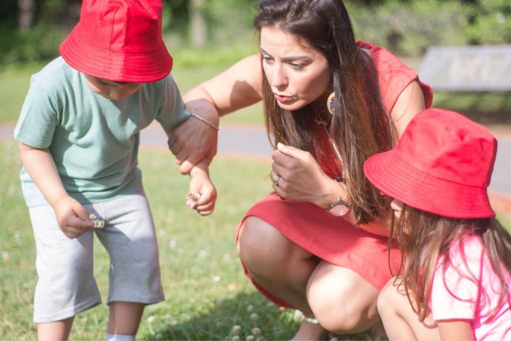 Children exploring nature with a nanny during an educational outdoor summer adventure.