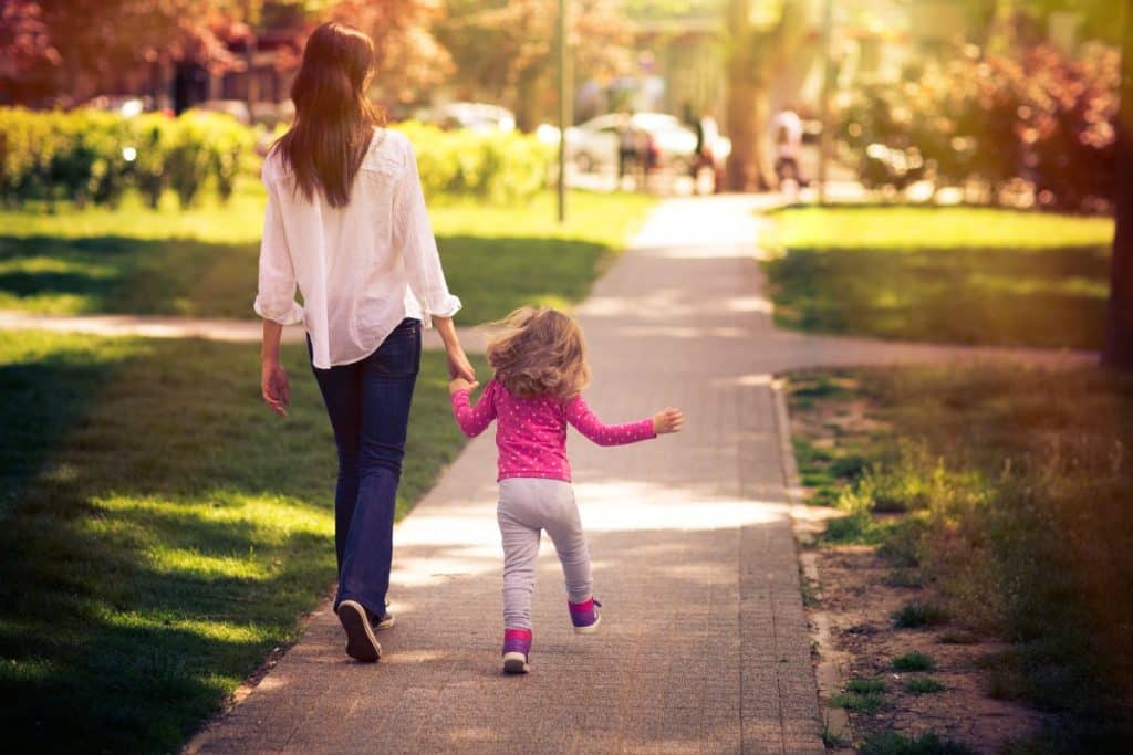 Professional nanny leading children on an outdoor summer adventure at a local park.