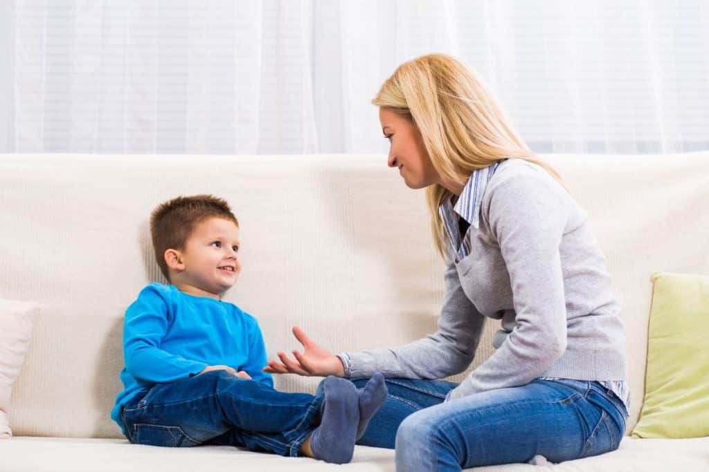 Caring nanny listening to a child talk about their school day and providing emotional support.