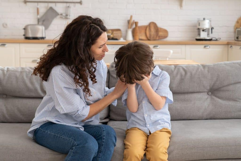 Caring nanny comforting a child and teaching healthy emotional regulation during a challenging moment.