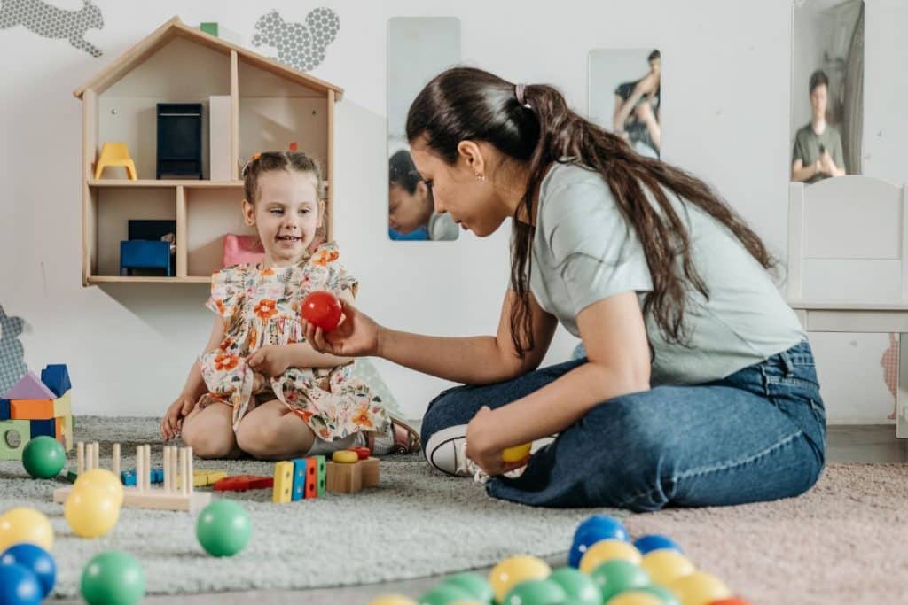 Nanny using age-appropriate communication while helping a child with an activity